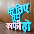 Turquoise and pink 3D text sculpture on a wooden surface